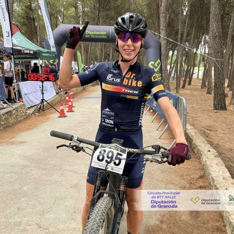 Ana Gay on her bike after the finish, raising one finger