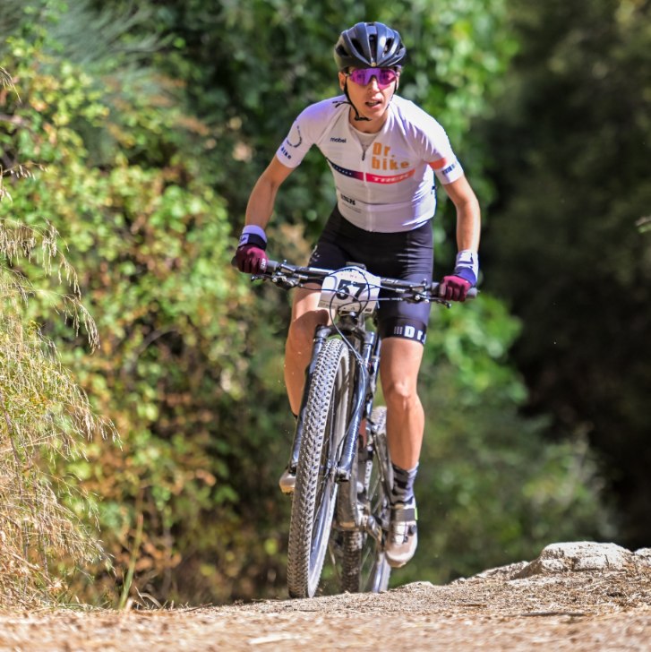 Ana Gay climbing a forest track on her mountain bike